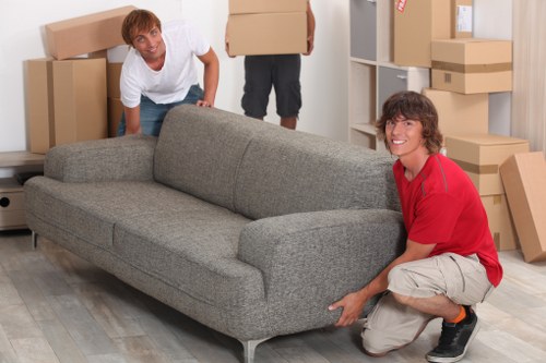 Movers carefully carrying furniture from a Merton home with tight access